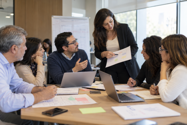 Equipo de profesionales participando en una capacitación empresarial junto a una facilitadora.
